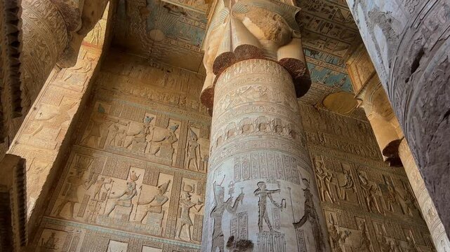 Interior view of painted columns and ornate ceiling in the hypostyle hall of the Temple of Hathor at Dendera, Egypt, revealing vibrant hieroglyphs and richly textured ancient decoration.