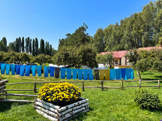 Colorful towels drying on clothesline in green rural garden on sunny summer day.