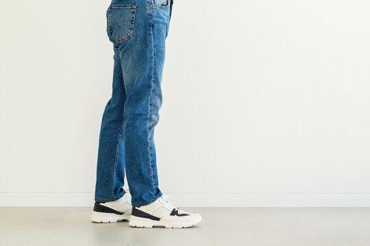 Lower half of Man with leg and foot wearing jeans and shoes on  white background