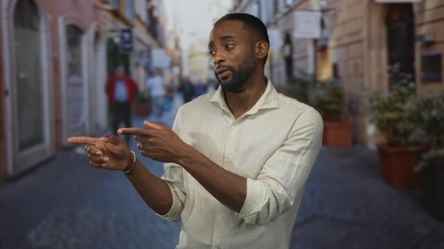 Man with rolled sleeves finger pointing to side on narrow cobblestone street with potted plants and blurred pedestrians; conversation persuasion calm.
