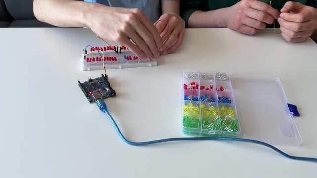 Boy assembling a colorful LED circuit on a breadboard connected to a microcontroller, hands learning electronics and programming during a STEM course for children.