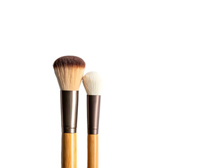 Two makeup brushes with wooden handles and soft bristles against black