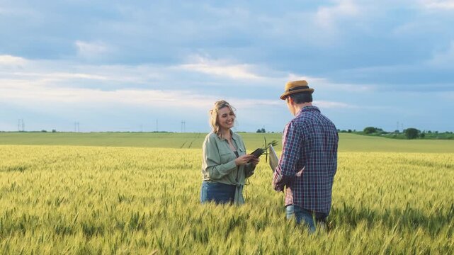 Two farmers standing in wheat field examining crop yield at sunset.