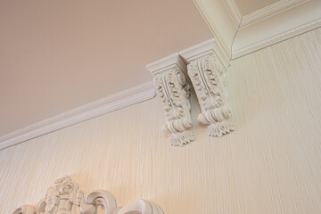 Elegant interior corner with ornate gypsum corbels, textured beige wall, decorative cornice, classical molding details, refined ceiling finish © evgeniykleymenov