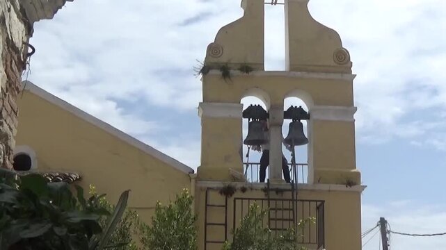 A man beats the bells on the bell tower with two hands. The bell tower of the Church of St. Nicholas. The end of church service