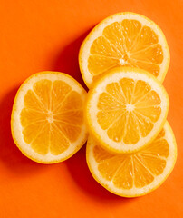 Fototapeta premium Slices of lemon placed on an orange background create a vibrant contrast in color and texture that draws attention