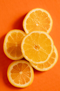 Lemon slices arranged on a bright orange background showing food colors and textures