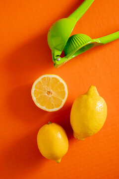 Fresh lemons and juicer on an orange background show kitchen preparation for a drink or dish in bright light