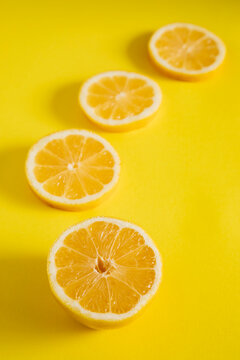 Slices of lemon arranged in a line on a bright yellow background for a bold visual effect