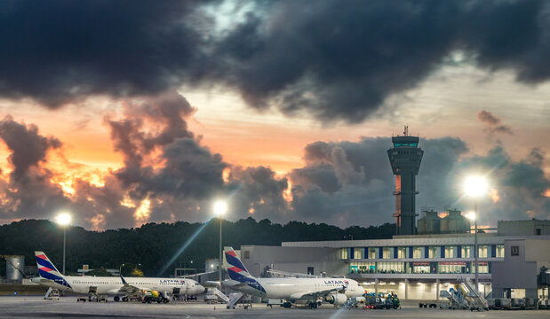 LATAM Airbus A320 parked at gate at Salvador Bahia Airport with the air traffic control tower in the background at dawn - Salvador, Brazil