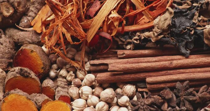 Close-up of fresh turmeric, ginger, and traditional spices arranged on a wooden surface. Natural herbal ingredients commonly used in cooking, alternative medicine, and wellness products.