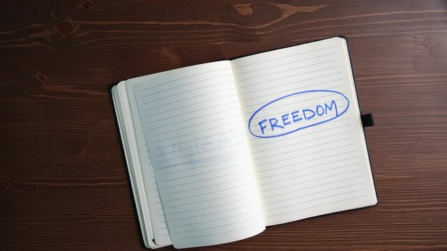 Woman Hand Highlighting the Word Freedom in Notebook Personal Growth and Independence Concept