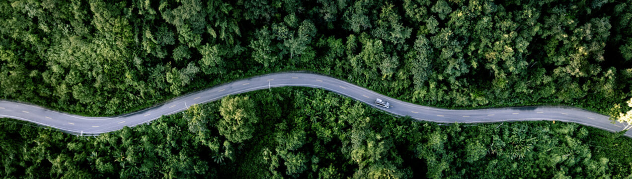 Aerial forest road with car creating abstract background for electric vehicle, ESG, sustainability and green investment business concepts.