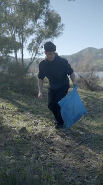 Young volunteer man cleaning plastic waste in nature