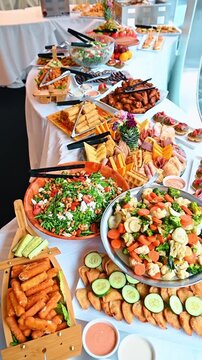 Large banquet buffet table with variety of appetizers and snacks. Long table filled with bowls of salad fried snacks and meat platters