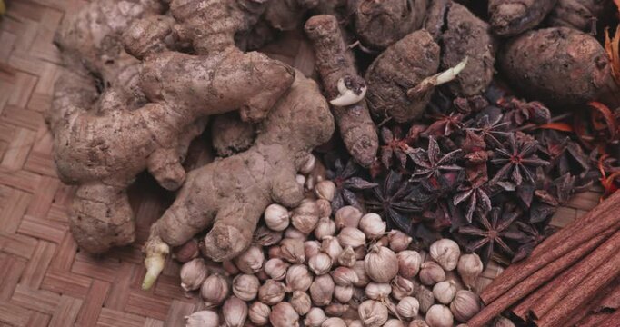 Close-up of fresh turmeric, ginger, and traditional spices arranged on a wooden surface. Natural herbal ingredients commonly used in cooking, alternative medicine, and wellness products.