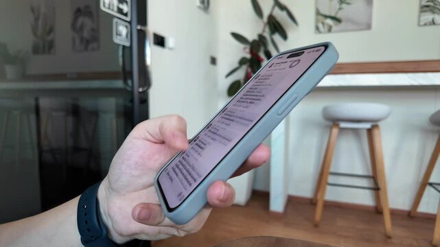 Holding and using a smartphone in your hand amidst the bright and simple atmosphere of a coffee shop perfectly aligns with the themes of technology, lifestyle, and remote work.