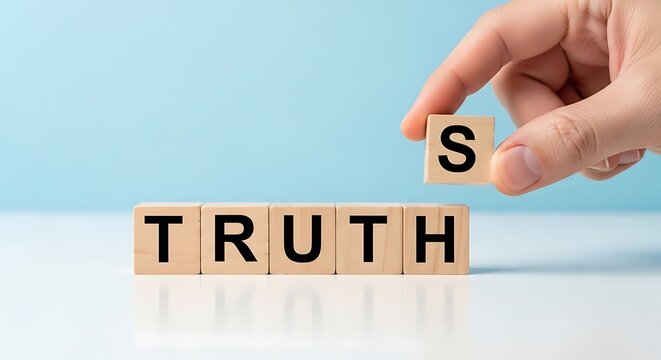 Hand holding wooden block with letter S above blocks spelling truth on white surface
