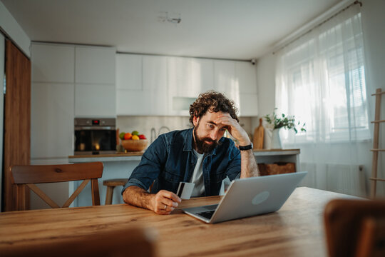 Stressed man experiencing financial worries using laptop