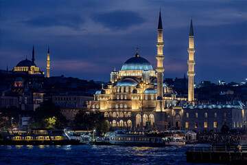 Obraz premium The New Mosque (Valide Sultan Mosque), beautifully illuminated against the Istanbul night sky, attracts the attention of visitors enjoying the picturesque view of the waterfront.