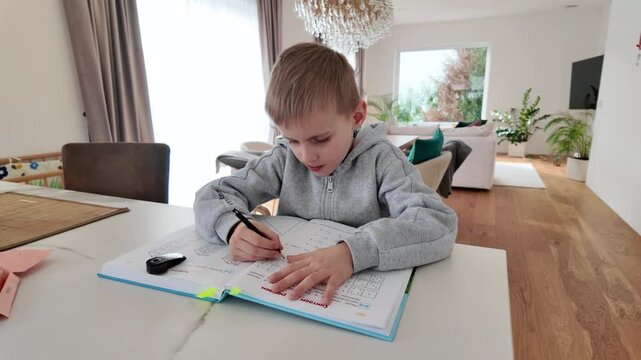 Five year old boy sitting with a book solving math exercises. Concept of early education, preschool learning, child development and preparation for school.