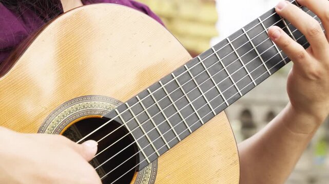 Horizontal extreme close-up focusing on the technical hand positioning of a classical guitarist. The image shows the fingers of the left hand pressing down on the nylon strings