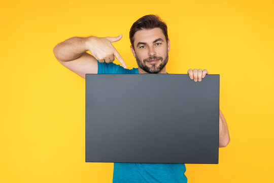 Man holds sign with copy space. Placard ready for copy space product. Sign to your copy space text. Man showing blank sign board on studio background, pointing finger. Empty copy space blank board.
