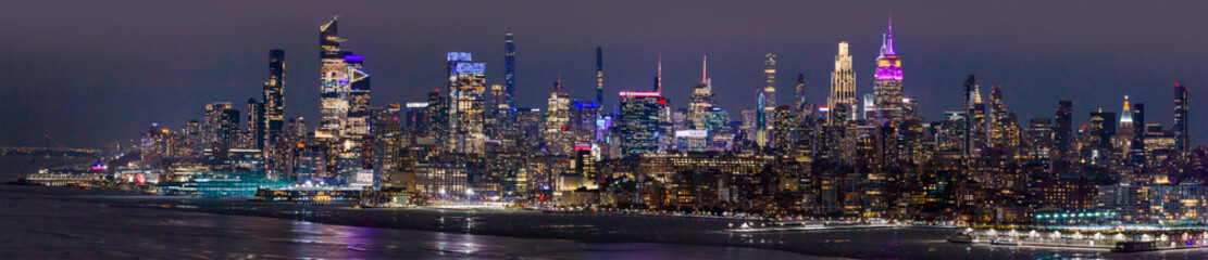 New York City wide night panorama with Manhattan. New York wide city night panorama with towers. Wide panorama of New York City skyline at night. New York night city wide panorama.