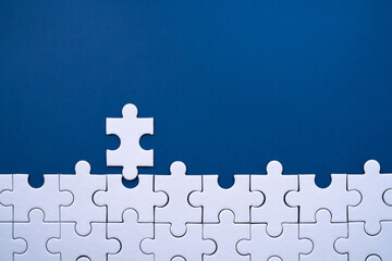 Fototapeta premium White puzzle pieces connecting to form a final missing section