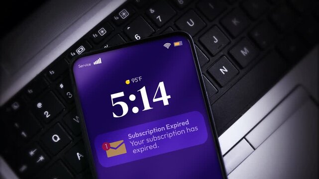 Smartphone shows subscription expired notification on laptop keyboard highlighting digital dependency in modern workspace, 4k
