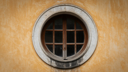 Fototapeta premium Circular Window With Wooden Bars On A Textured Yellow Exterior Wall Of A Classic Building