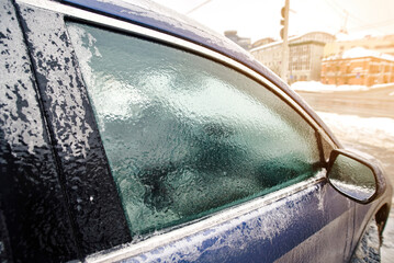 Frozen car window. Extreme winter weather conditions, car trapped under heavy coating of ice from freezing rain event. Difficult situation for morning commuters in the city. Selective focus