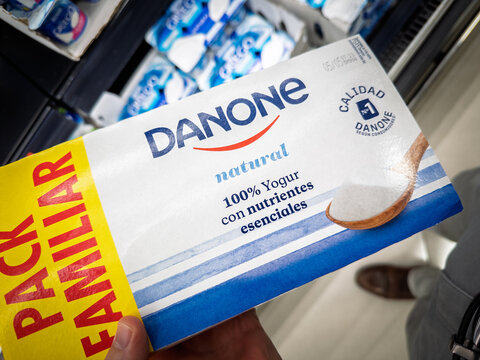 VALENCIA, SPAIN - APRIL 5, 2025: Close-up of a hand holding a Danone natural yogurt in a supermarket in Valencia, Danone is a french food corporation.