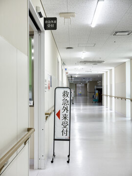 Hospital corridor with information board indicating "Outpatient reception of the emergency department" in Japanese language