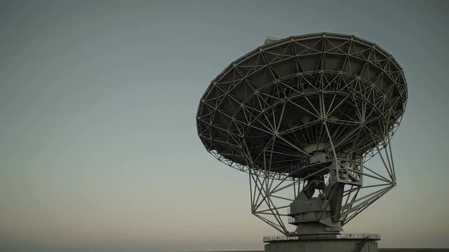 A high-angle shot of a massive metallic parabolic antenna used for space communication and astronomical research. This asset is perfect for themes involving science, global communication, and space ex