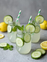 Fototapeta premium Refreshing Cucumber Lemonade In Mason Jars With Mint And Lemon Slices On A Rustic Background