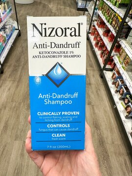 A hand holding Nizoral Anti-Dandruff Shampoo in a hair care aisle at a store. Valparaiso, IN USA - February 23, 2026