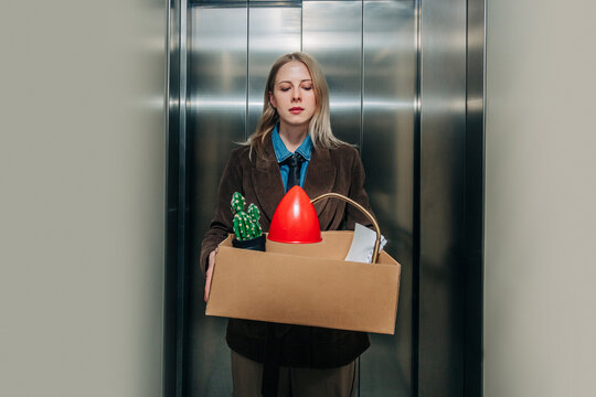 Woman standing in elevator with box after being fired from job