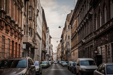 Typical street in central Budapest, Hungary, lined with parked cars and dense rows of old residential buildings, showing urban architecture and everyday city life in the downtown area.