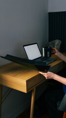Naklejka premium Person working at a wooden desk with a laptop and a mug that says work