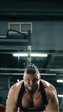 Focused strength athlete straining through a heavy lift in a modern gym, showcasing muscular physique, determination, and grit under dramatic lighting in a low-angle training scene