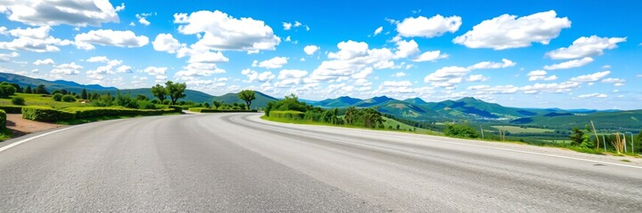 Winding asphalt road through lush green hills under blue sky with fluffy white clouds featuring mountain range in distance and vibrant summer nature scenery view