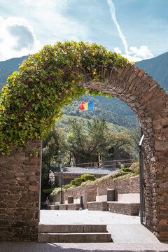 Stone Arch of Casa de la Vall in Andorra La Vella Old Town, with Andorra flag in the background