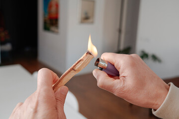 a man lights a sandalwood stick indoors