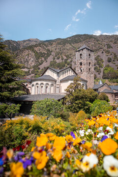 Exterior of St Esteve of Andorra Church with a garden and Pyrenees mountains in the background in Andorra la Vella old town on a sunny day