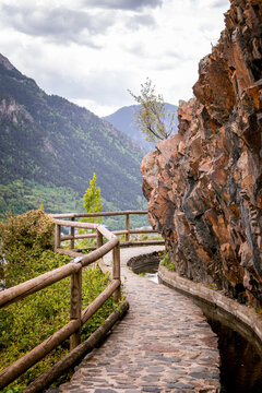 Trees and stone path on Rec del Sola trail in Andorra la Vella on a sunny day