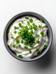 Obraz premium Creamy sour cream dip topped with fresh chopped chive in small ceramic bowl, perfect for appetizer or snack, on white background