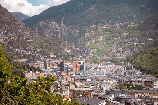 Above view of Andorra la Vella town and buildings seen from Rec del Sola trail with Pyrenees mountain in the background on a sunny day