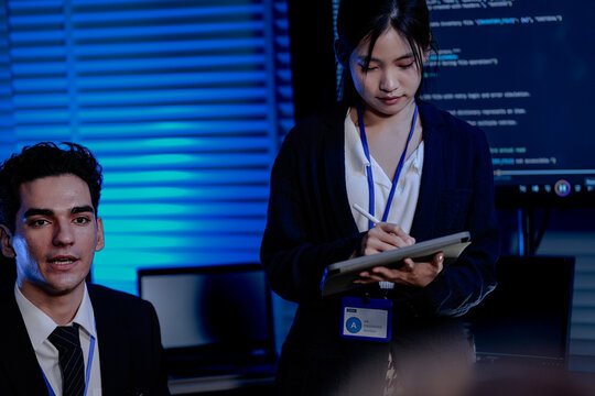 An Indian female developer leads a code review, holding a report. She explains a Python script for an AI or cybersecurity system to her team in a dark SOC Security Operations Center