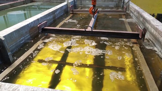 Immersion cleaning: Metal cabinets being lowered into chemical tanks for phosphating.